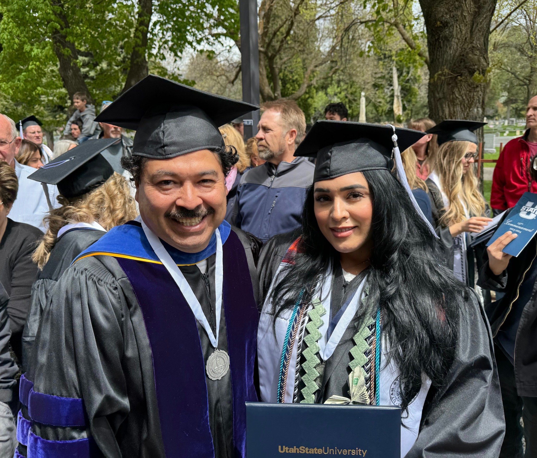 Jasmine Morales, '23 Sociology graduate, modeling the blue Undergraduate Research Scholar graduation cord with her research mentor Dr. Crescencio López-González